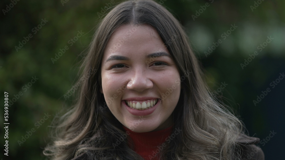 One happy casual Brazilian hispanic young woman laughing and smiling portrait face closeup standing outdoors One happy casual Brazilian hispanic young woman laughing and smiling portrait face closeup standing outdoors