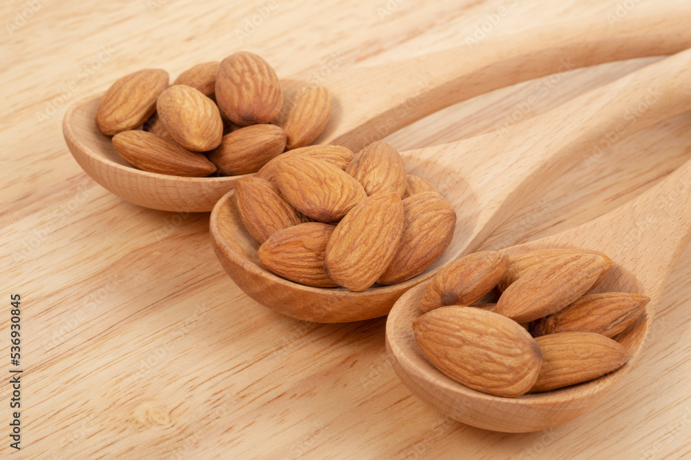Almonds in wooden spoon on wooden background. Healthy food concept. Almonds in wooden spoon on wooden background. Healthy food concept.