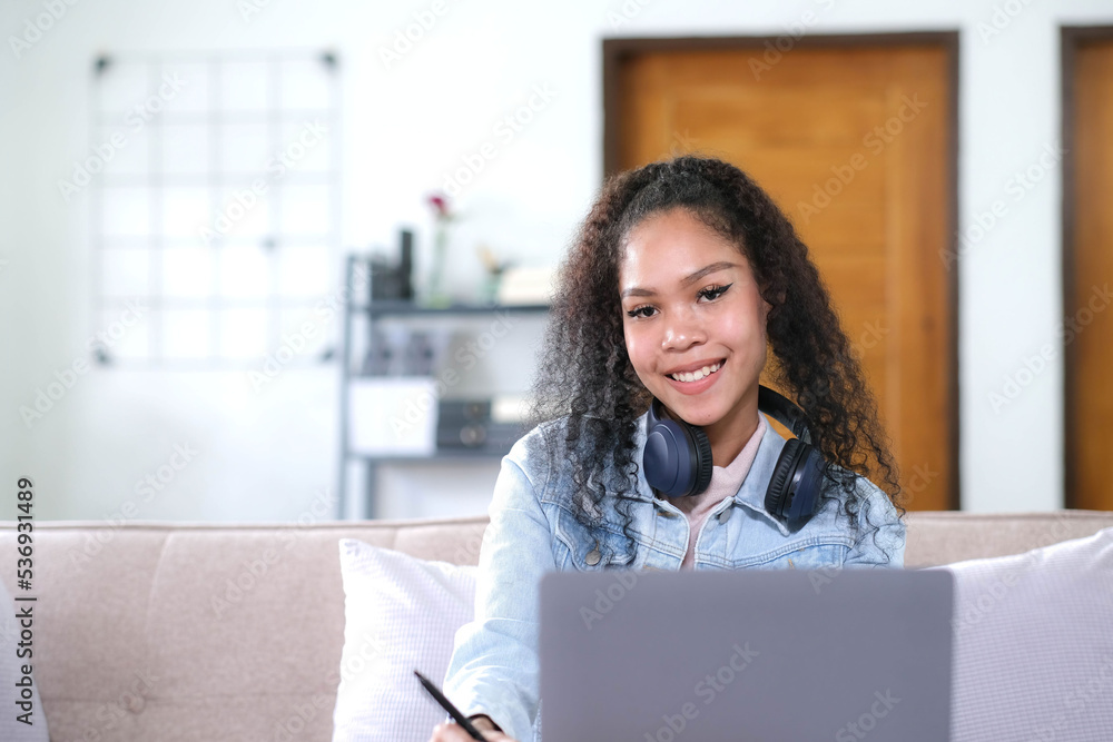Smiling Asian young female using headphones looking at laptop screen listen and learning online courses. Smiling Asian young female using headphones looking at laptop screen listen and learning online courses.