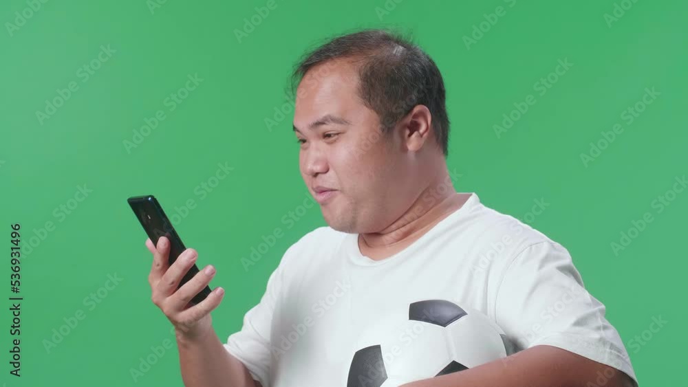 Close Up Side View Of Asian Man With A Ball Screaming Goal Celebrating While Cheering Soccer On Smartphone In Green Screen Background
Close Up Side View Of Asian Man With A Ball Screaming Goal Celebrating While Cheering Soccer On Smartphone In Green Screen Background
