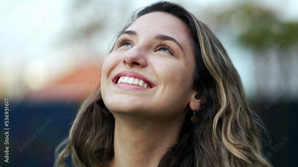 Happy hopeful young millennial woman standing outside smiling looking at sky with FAITH Happy hopeful young millennial woman standing outside smiling looking at sky with FAITH
