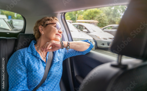Obraz na płótnie Beautiful happy senior woman in a blue blouse in the passenger seat in a car enjoying a trip w salonie