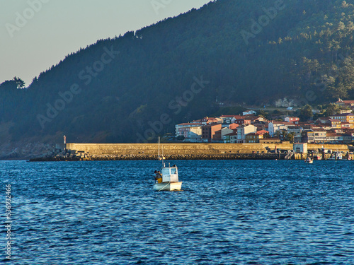 Unrecognisable fishermen fishing on the boat in the Galician estuary at sunset