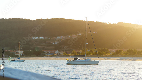 View from the sea of sailboats in the water and people walking on the beach