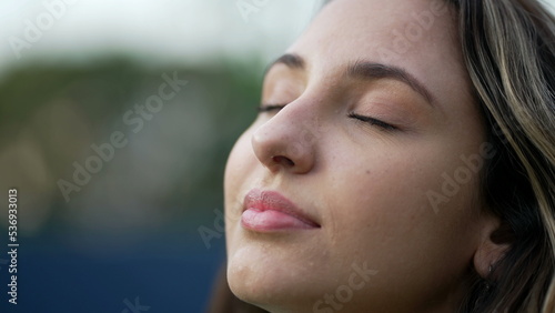 Young hispanic woman closing eyes in meditation. Millennial 20s girl opening eyes smiling. Closeup female person face