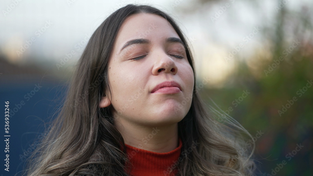 Serene peaceful young woman closing eyes in contemplation. Spiritual meditative millennial girl opening eye