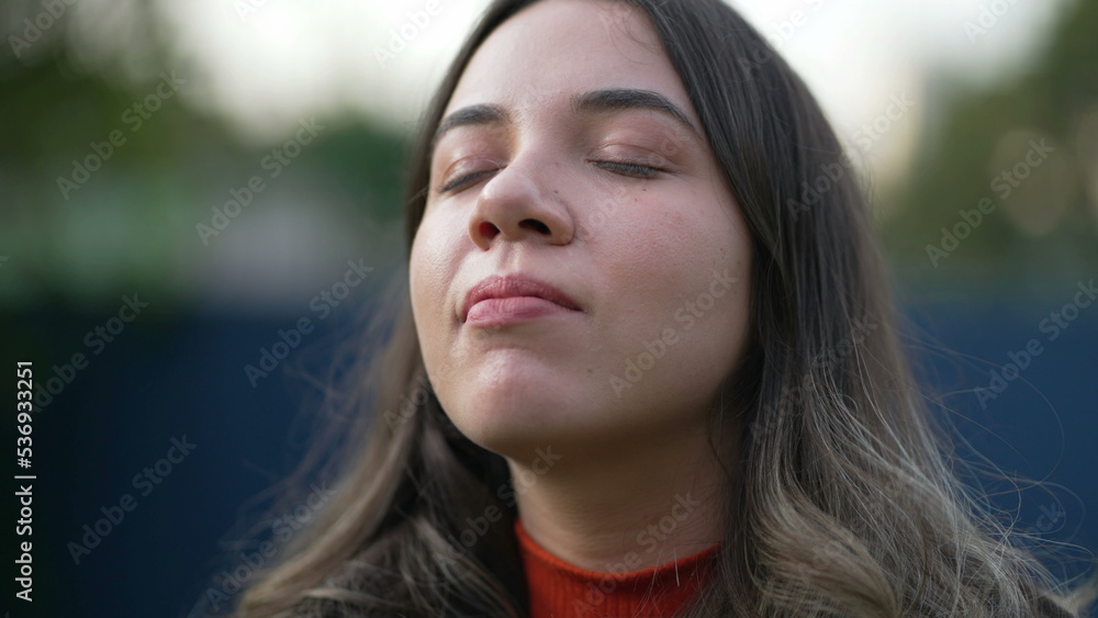 Serene peaceful young woman closing eyes in contemplation. Spiritual meditative millennial girl opening eye Serene peaceful young woman closing eyes in contemplation. Spiritual meditative millennial girl opening eye