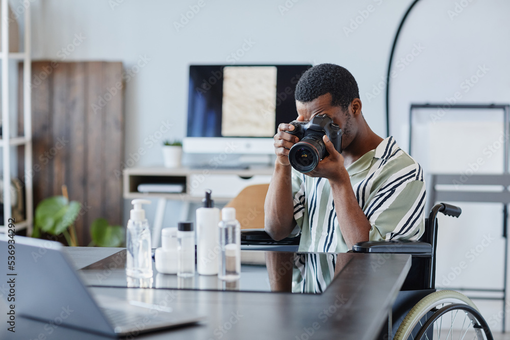 Portrait of young black man as photographer with disability taking product pictures in photo studio Portrait of young black man as photographer with disability taking product pictures in photo studio