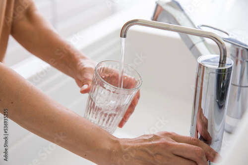 浄水器からコップに水を入れる女性の手元 photo