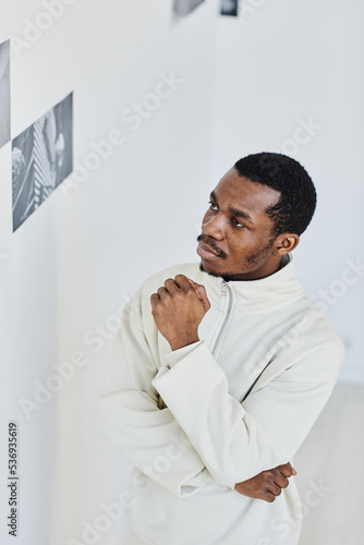 Minimal portrait of handsome black man looking at images in photo gallery and enjoying art