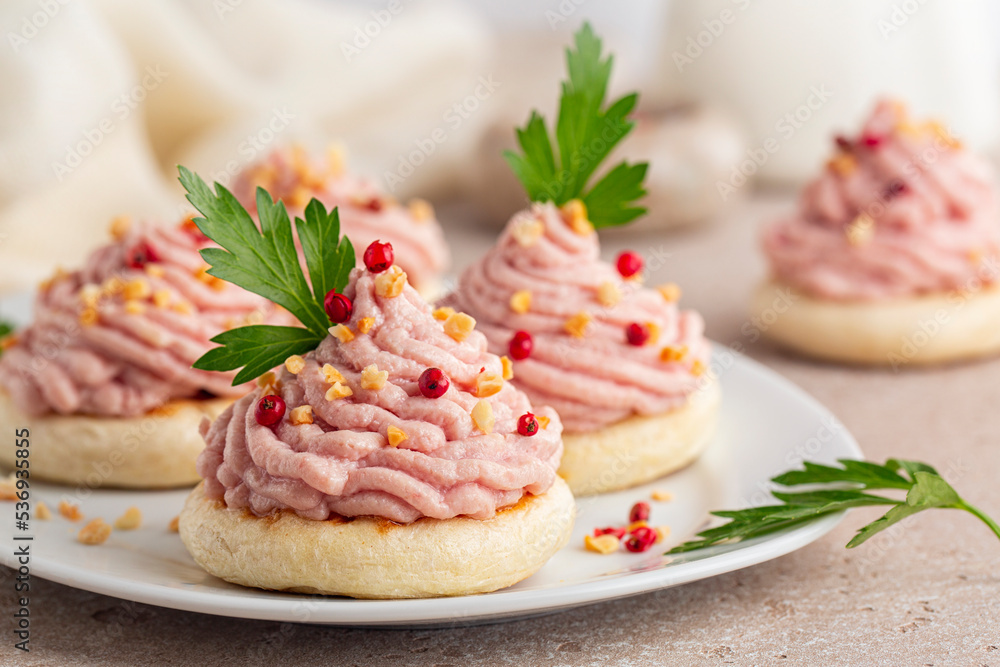 Beautiful Italian canapes with mortadella and ricotta cream mousse or Spuma di mortadella on a small tigelle bread. Appetizer or snacks for a festive table. Beautiful Italian canapes with mortadella and ricotta cream mousse or Spuma di mortadella on a small tigelle bread. Appetizer or snacks for a festive table.