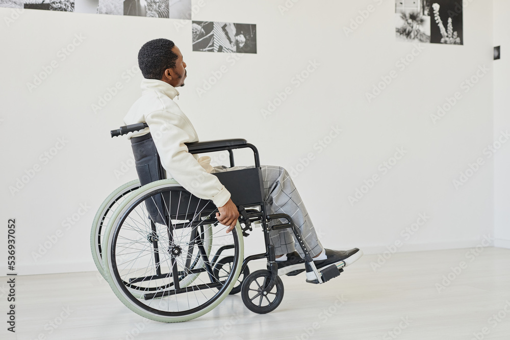 Black young man using wheelchair while visiting modern art gallery, copy space Black young man using wheelchair while visiting modern art gallery, copy space