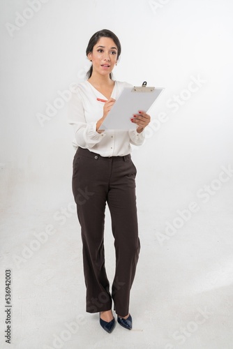 Studio portrait photo of a young beautiful elegant Brazilian female businesswoman lady wearing smart casual business suit with folder board and pen posing with a series moments of emotion and gesture