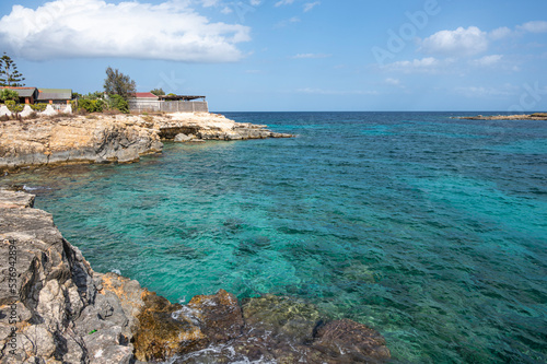 The beautiful Ognina beach in Syracuse with turquoise and green water and a small island in front of it