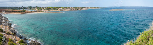 Extra wide angle view of The beautiful Ognina beach in Syracuse with turquoise and green water and a small island in front of it