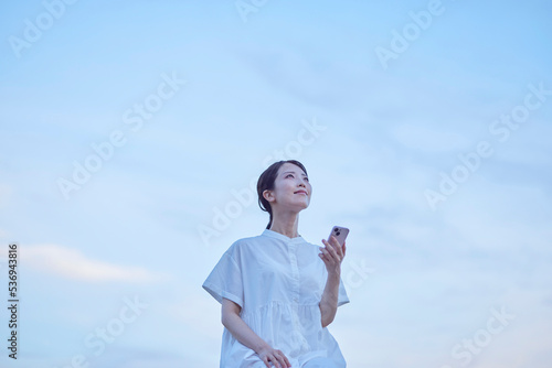 夕暮れ時の青空と白いワンピースを着た女性 photo