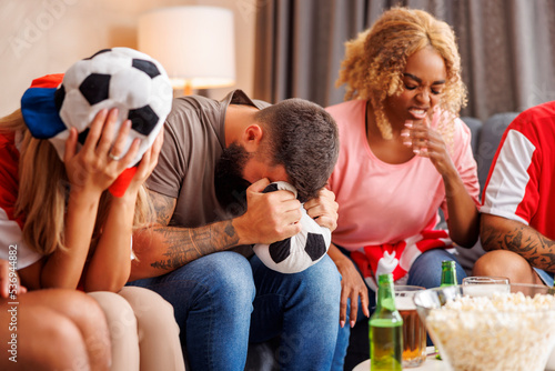 Football fans dissapointed after their team missing the goal while watching the game on TV
