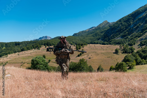 army soldier holding a sniper rifle with scope and walking in the forest. war, army, technology and people concept. 