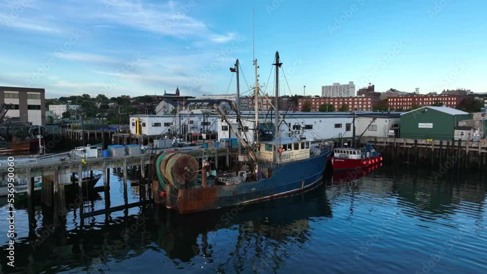 Fishing boat with nets in dock at Portland Maine USA. Lobster boats and fishing industry theme. Aerial in golden hour light. Fishing boat with nets in dock at Portland Maine USA. Lobster boats and fishing industry theme. Aerial in golden hour light.