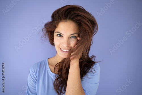 athletic woman with purple shirt in front of purple background with long dark hair © epiximages