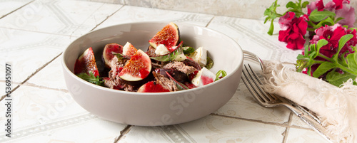 bowl of salad with duck breast and figs with raspberry sauce on the table photo