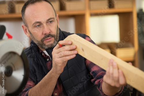 man looks at a piece of wood in workshop photo