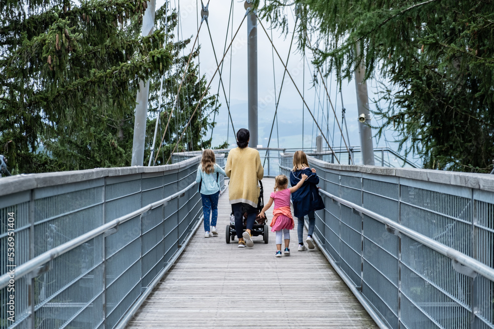 Woman with 3 Kids and stroller walking on bridge Woman with 3 Kids and stroller walking on bridge