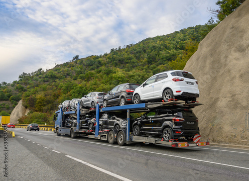 Car transport by road. Truck transporting new cars for sale. No brand or logo.