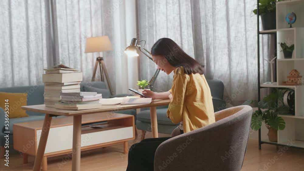 Side View Of Young Asian Female Studying At Home Smiling And Using Smartphone While Reading Books On The Table
Side View Of Young Asian Female Studying At Home Smiling And Using Smartphone While Reading Books On The Table