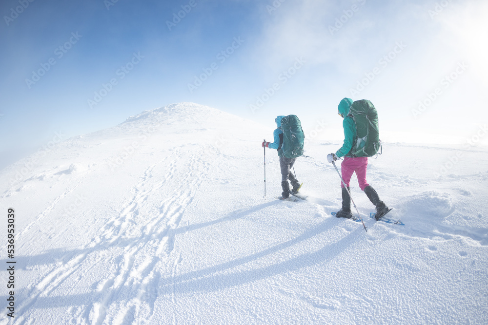 Two women walk in snowshoes in the snow