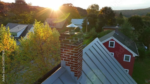 Red brick chimney on home rooftop. Aerial in autumn. Utility bills and home heating theme. Houses in residential district in autumn. photo