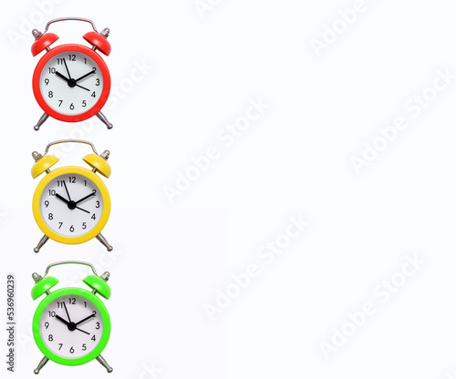 Three multi-colored traffic light alarm clocks on a white background with free space for text. Green yellow and red mechanical alarm clock. The concept of punctuality and responsibility