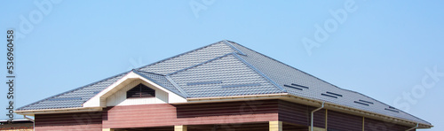 Roofs of houses from a metal profile against the sky. Roofing. Metal tiles on the roofs of houses.