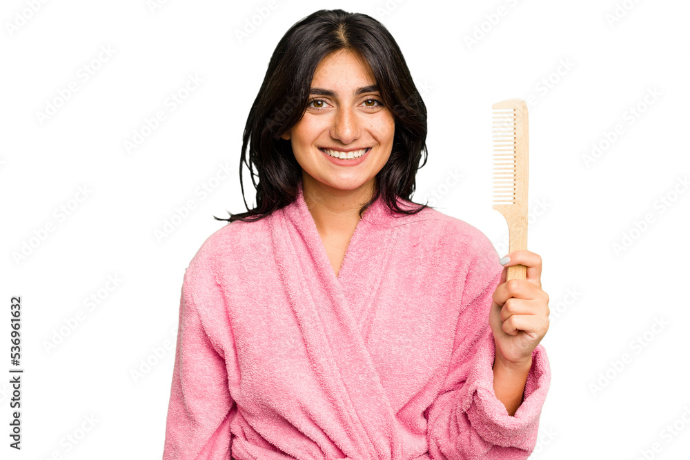 Young woman in a bathrobe holding an hair comb isolated happy, smiling and cheerful.
