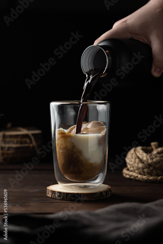 Cup of milk pouring coffee in low key
