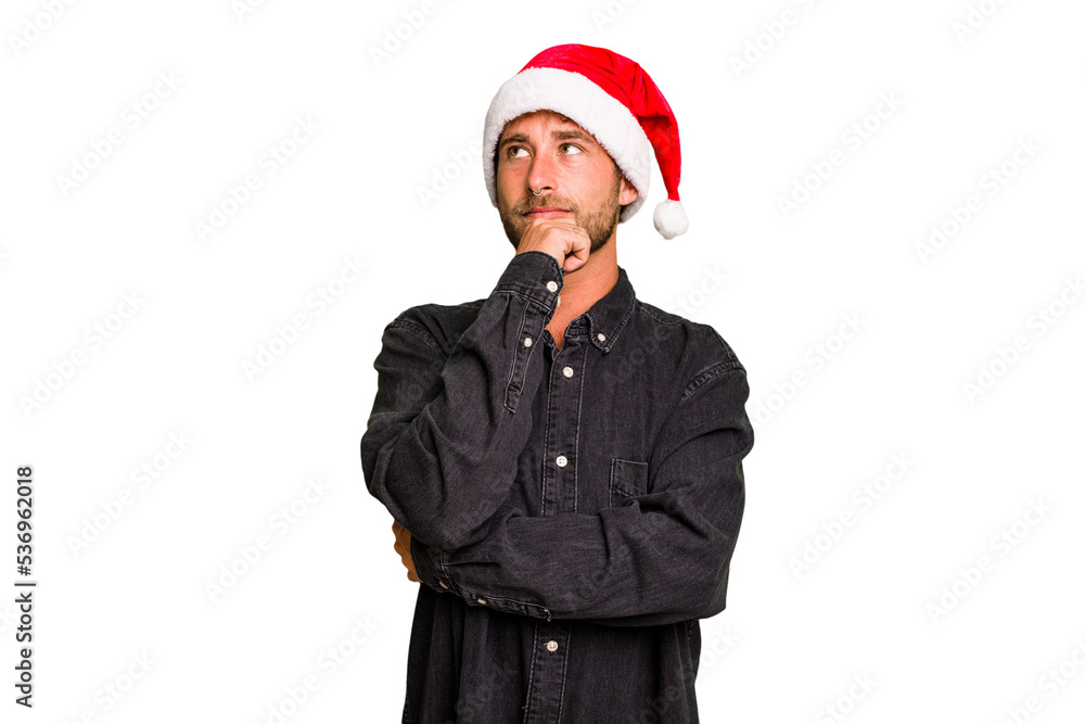 Young caucasian man celebrating Christmas wearing a santa hat isolated looking sideways with doubtful and skeptical expression. Young caucasian man celebrating Christmas wearing a santa hat isolated looking sideways with doubtful and skeptical expression.