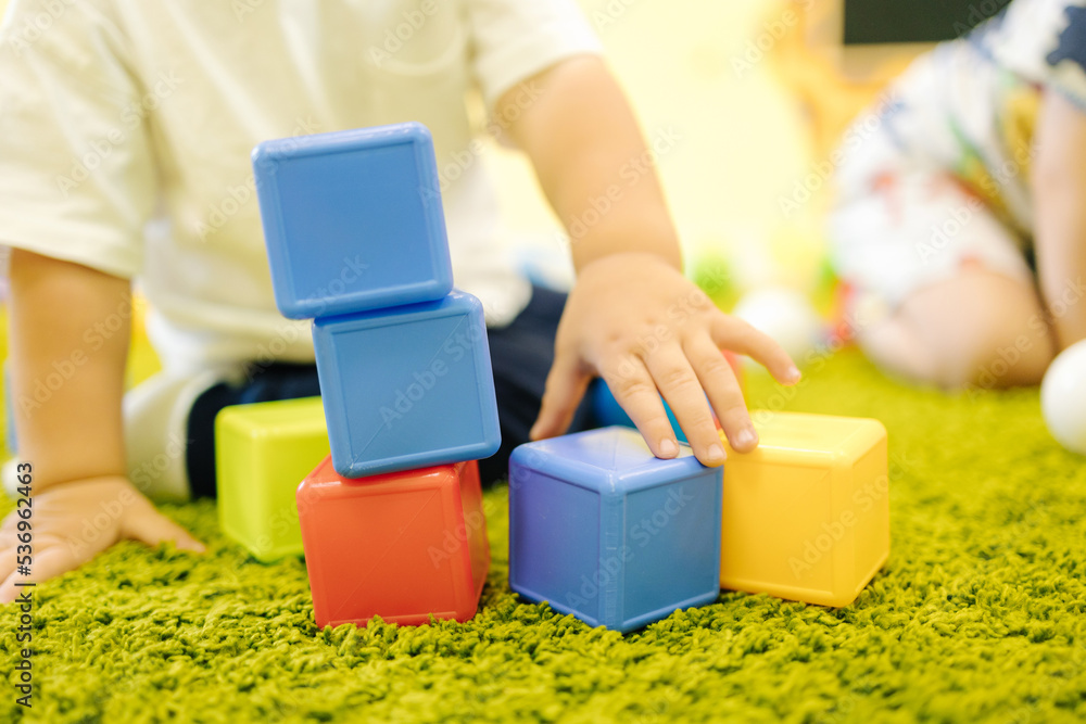 Three Cubes Builds Little boy builds a tower of cubes. Kindergarten Stock Photo | Adobe Stock