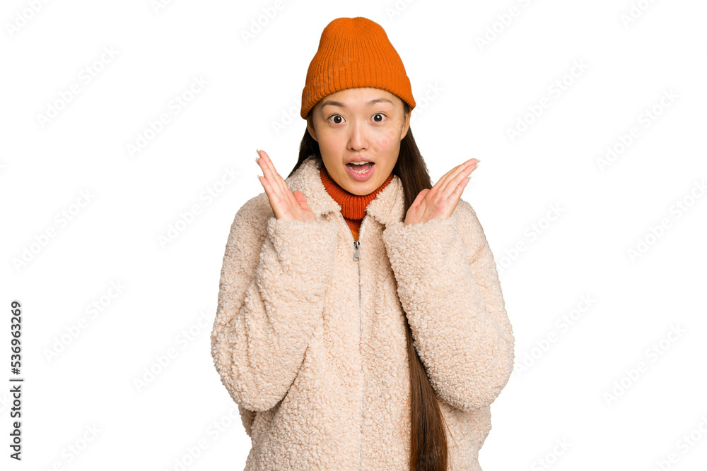 Young asian woman wearing winter clothes isolated on green chroma background surprised and shocked.