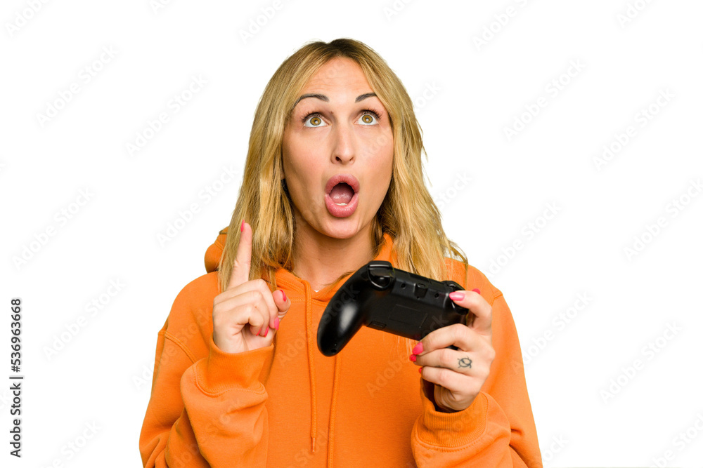 Young caucasian gamer woman holding a game controller isolated on green chroma background pointing upside with opened mouth. Young caucasian gamer woman holding a game controller isolated on green chroma background pointing upside with opened mouth.