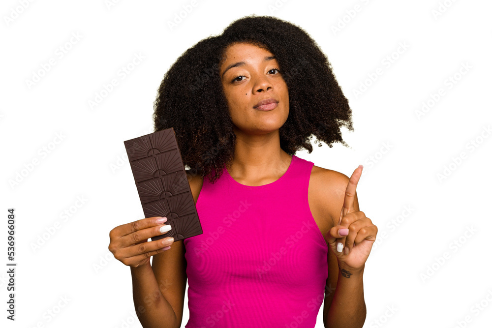 Young African American woman holding a chocolate bar isolated showing number one with finger. Young African American woman holding a chocolate bar isolated showing number one with finger.