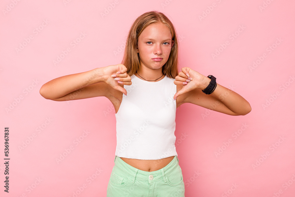 Caucasian teen girl isolated on pink background showing thumb down, disappointment concept.
