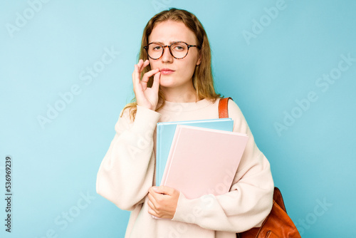 Young student caucasian woman isolated on blue background with fingers on lips keeping a secret.