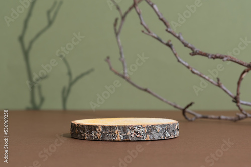 Wooden slice podium on a brown table on a green background with the shadow of tree branches. Premium empty scene for product promotion, beauty, natural eco cosmetic. Showcase, display case.