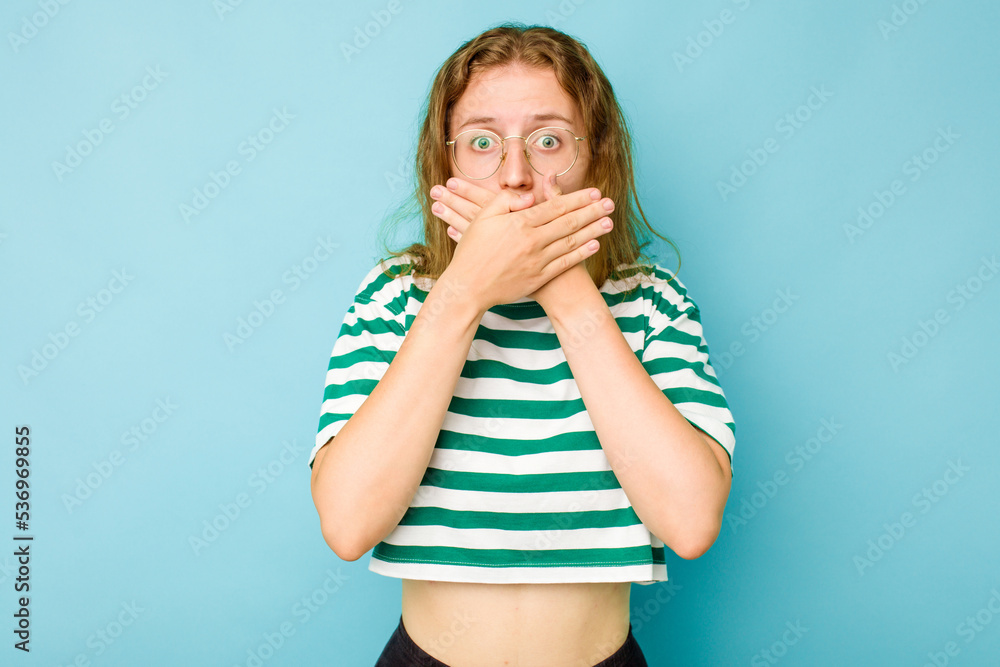 Young caucasian woman isolated on blue background covering mouth with hands looking worried. Young caucasian woman isolated on blue background covering mouth with hands looking worried.
