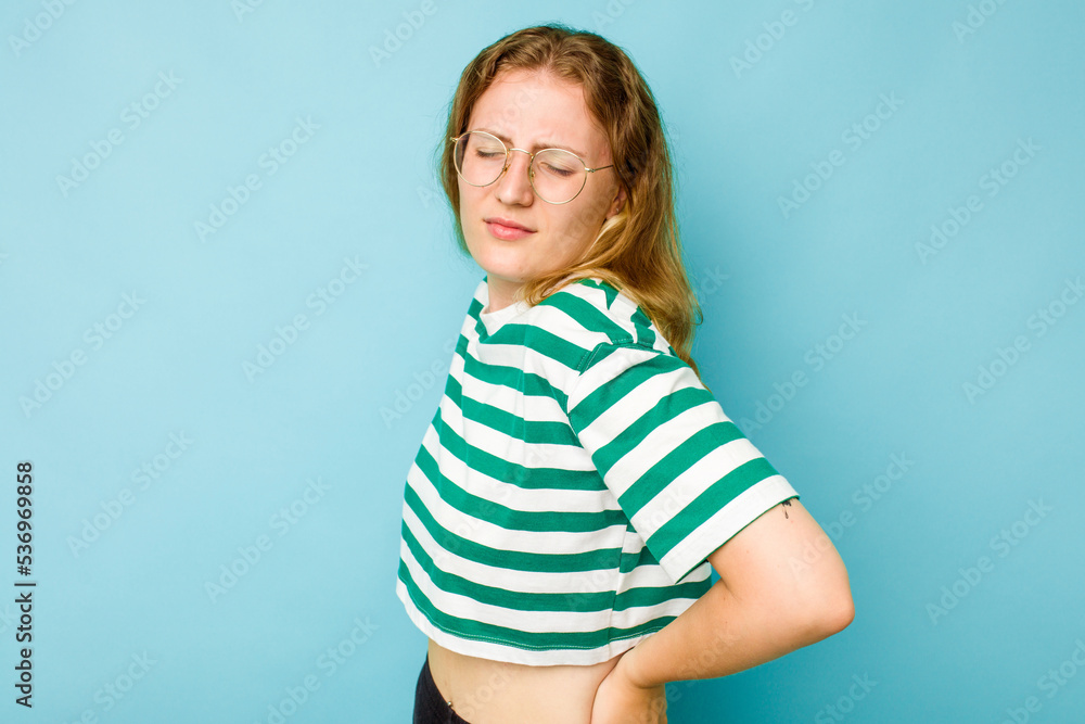Young caucasian woman isolated on blue background suffering a back pain. Young caucasian woman isolated on blue background suffering a back pain.