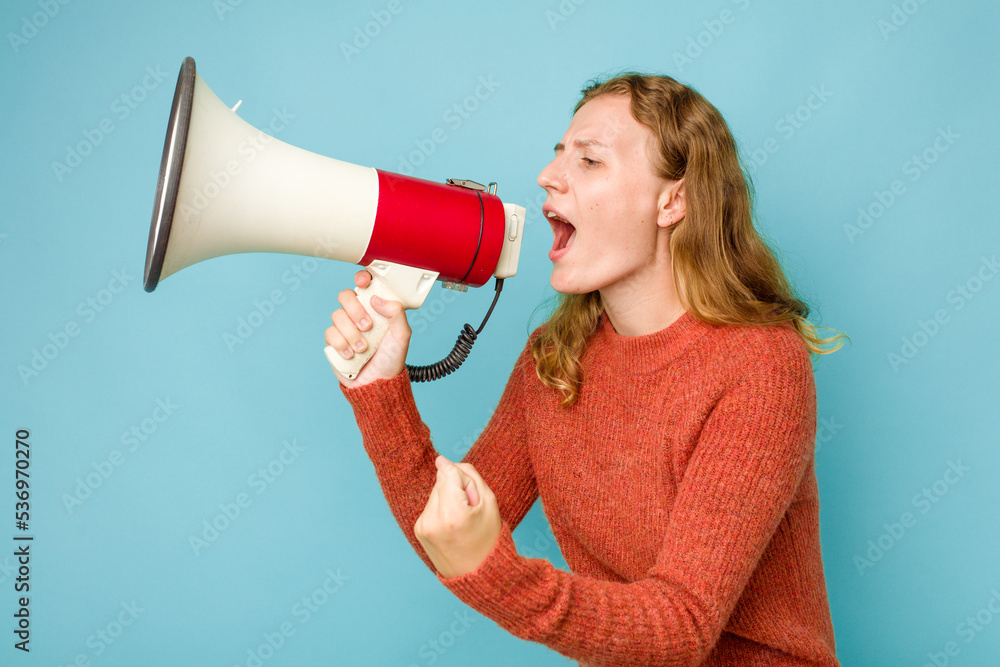 Young caucasian woman holding megaphone isolated on blue background Young caucasian woman holding megaphone isolated on blue background
