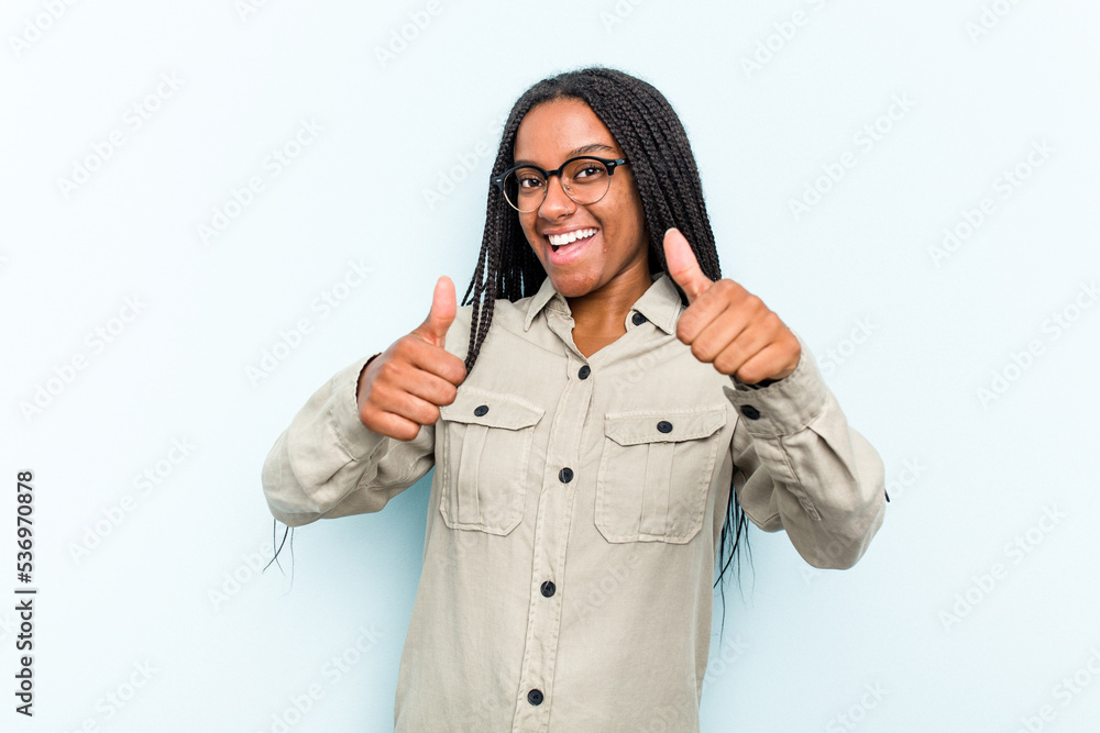 Young African American woman with braids hair isolated on blue background raising both thumbs up, smiling and confident. Young African American woman with braids hair isolated on blue background raising both thumbs up, smiling and confident.