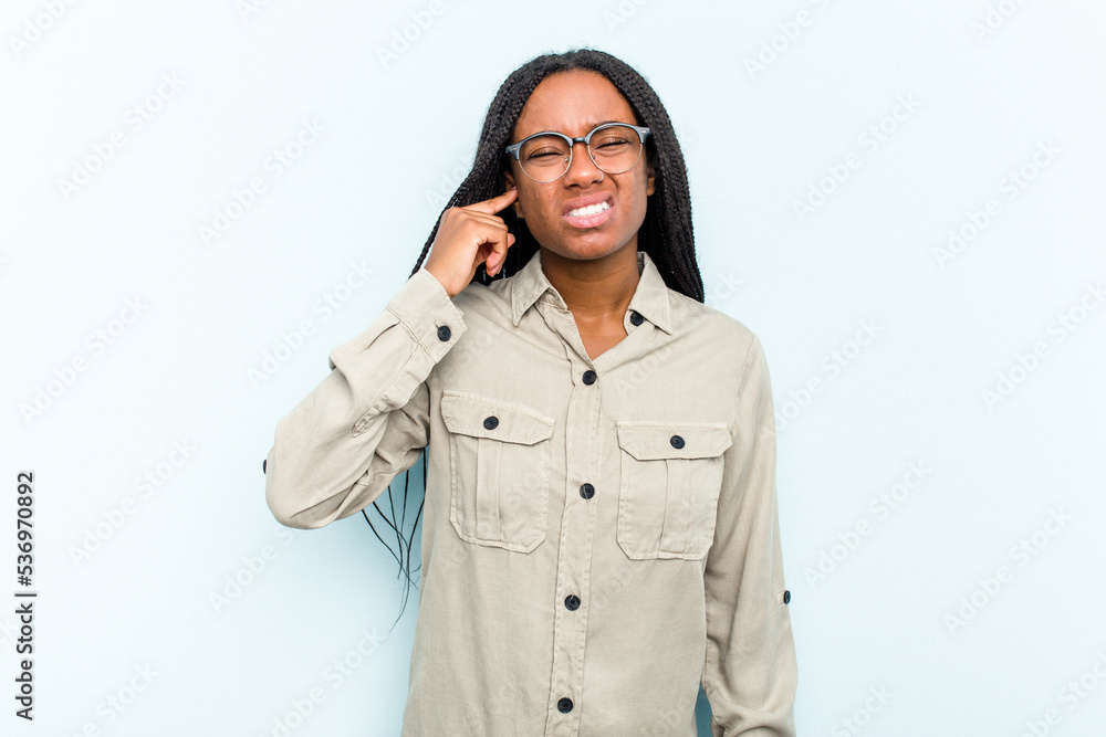 Young African American woman with braids hair isolated on blue background covering ears with fingers, stressed and desperate by a loudly ambient. Young African American woman with braids hair isolated on blue background covering ears with fingers, stressed and desperate by a loudly ambient.