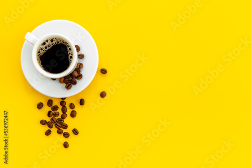 White cup of hot black espresso with coffee beans