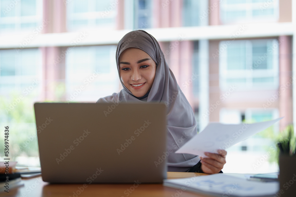 eautiful Muslim woman using computer and documents working in office eautiful Muslim woman using computer and documents working in office
